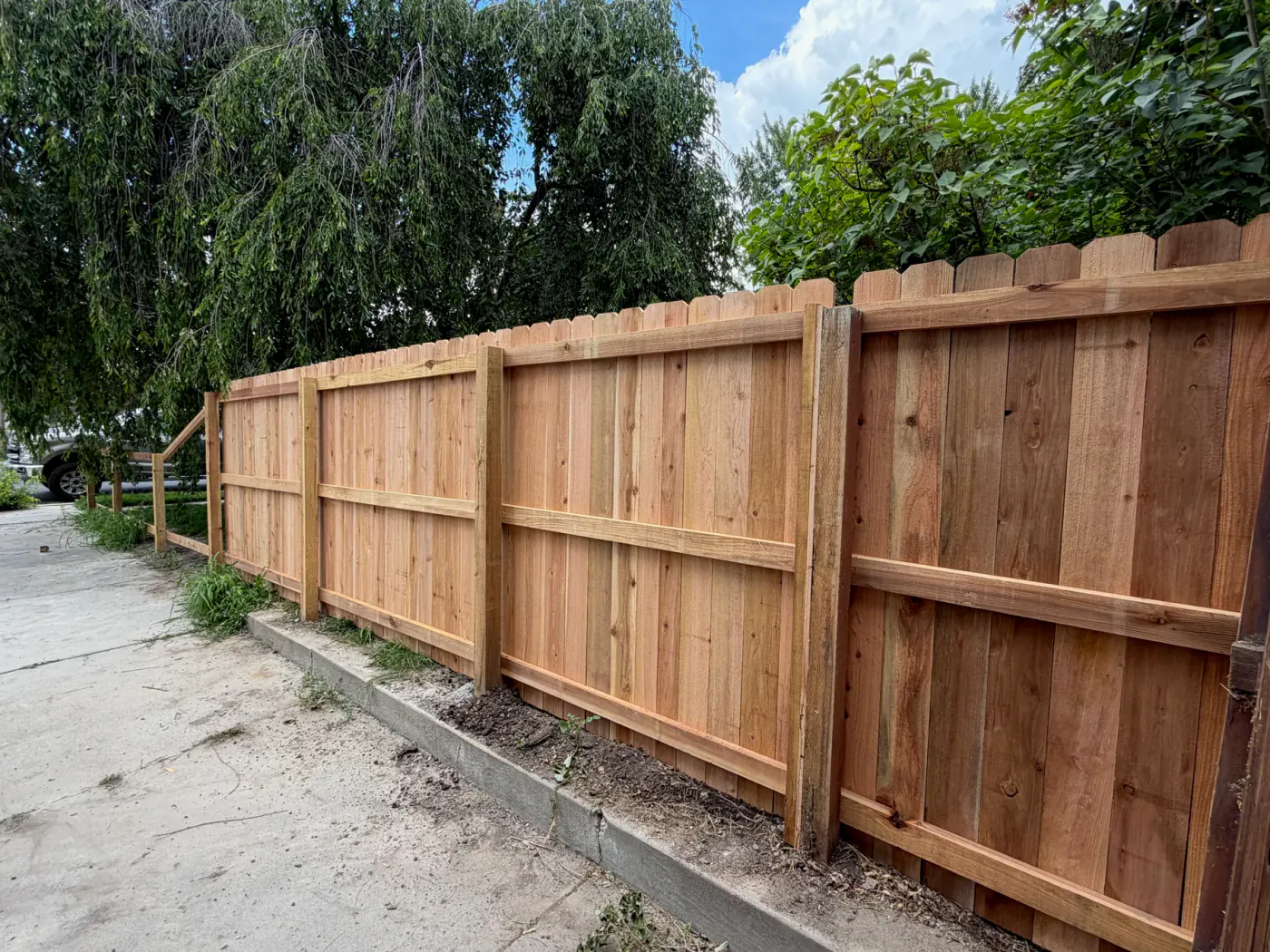 New cedar privacy fence installed beside a residential driveway in Sandy, Utah